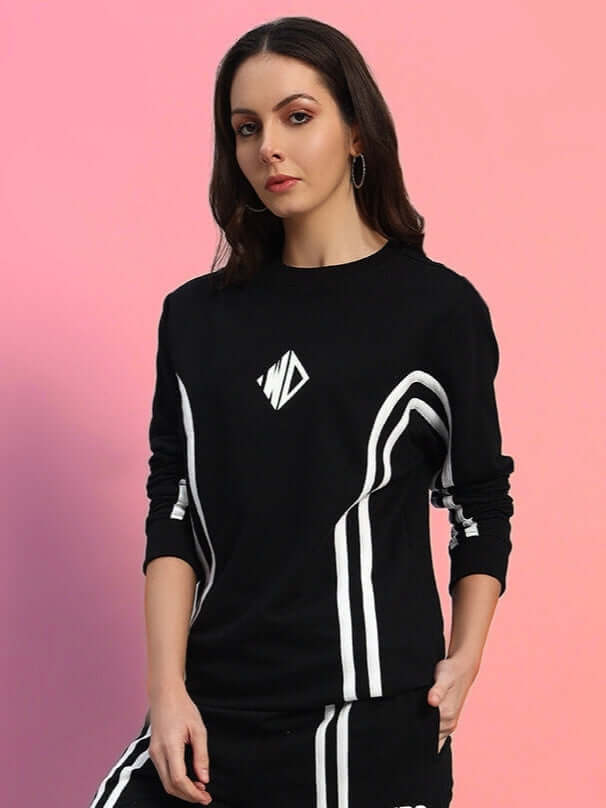 Woman modeling WOMEN'S OUTLOOK SWEATSHIRT BLACK WITH WHITE STRIPE, showcasing casual streetwear on pink background.