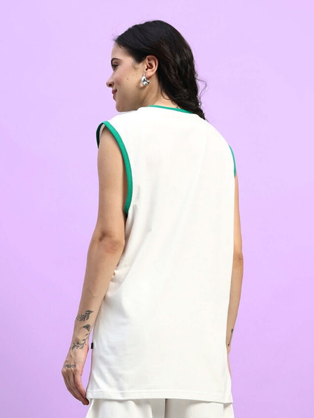 Back view of model wearing WOMEN'S DRIBBLE OVER-SIZED T-SHIRT OFF-WHITE, showing trendy summer fashion on light purple background.