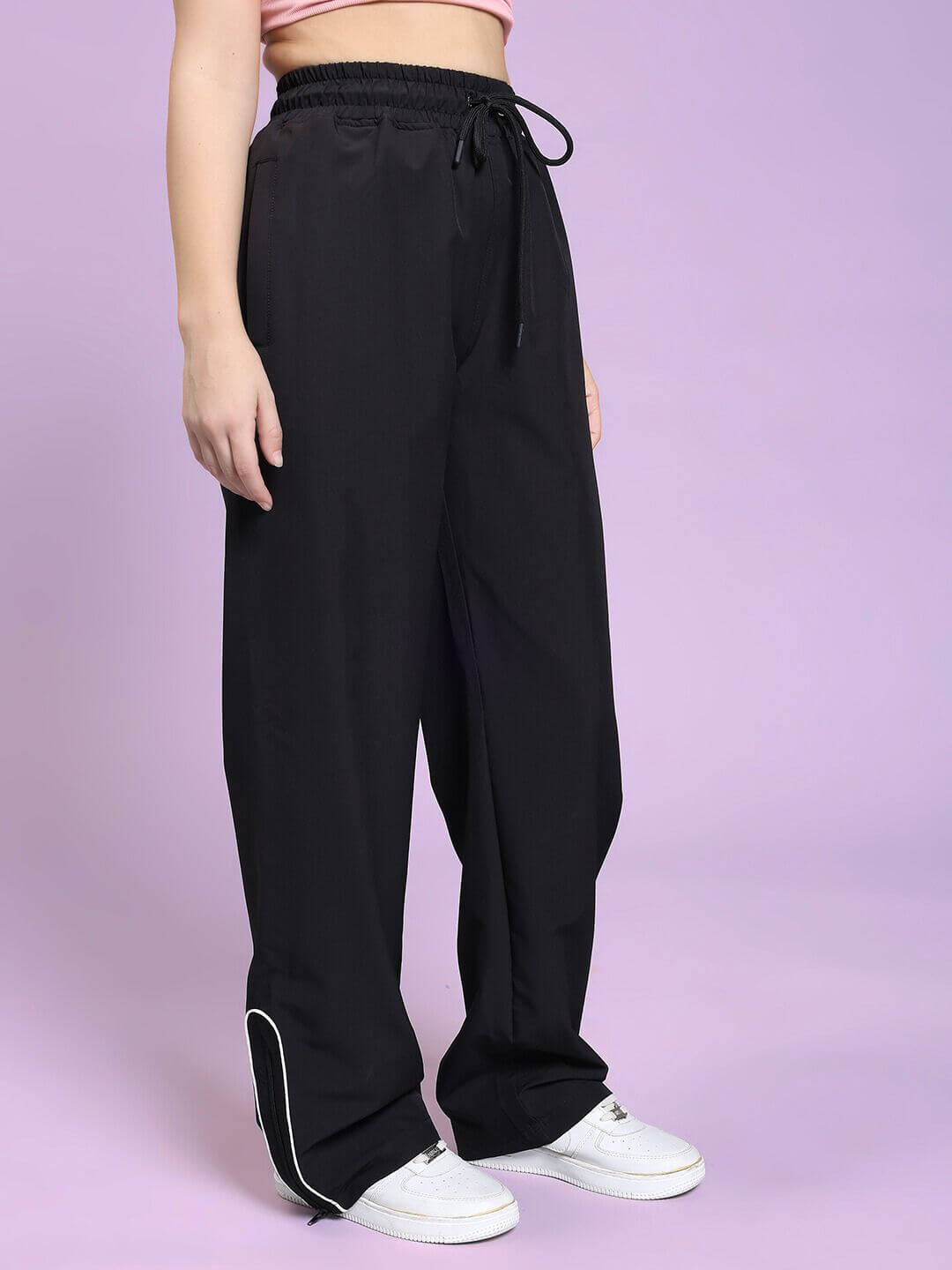 Model wearing WOMEN PERFACT RELAXED-FIT JOGGER BLACK, showcasing sleek design and modern comfort on lavender backdrop.