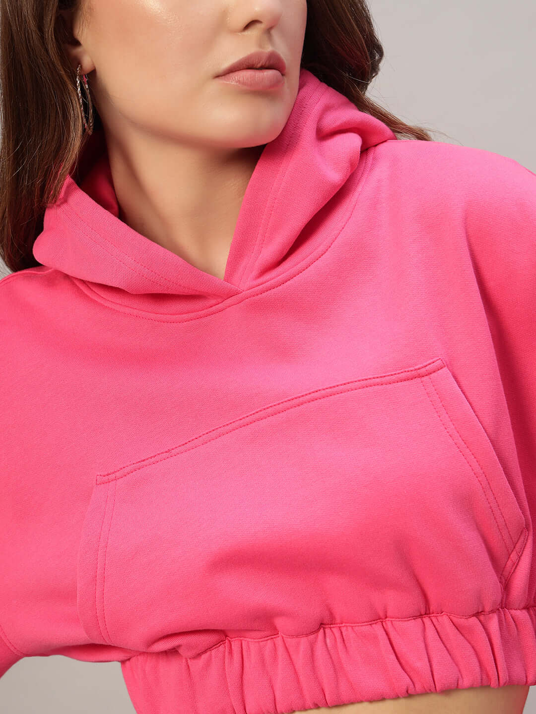 Woman wearing WOMEN CHARM OVER-SIZED FLEECE CROP HOODIES PINK, showcasing its relaxed fit and vibrant color.