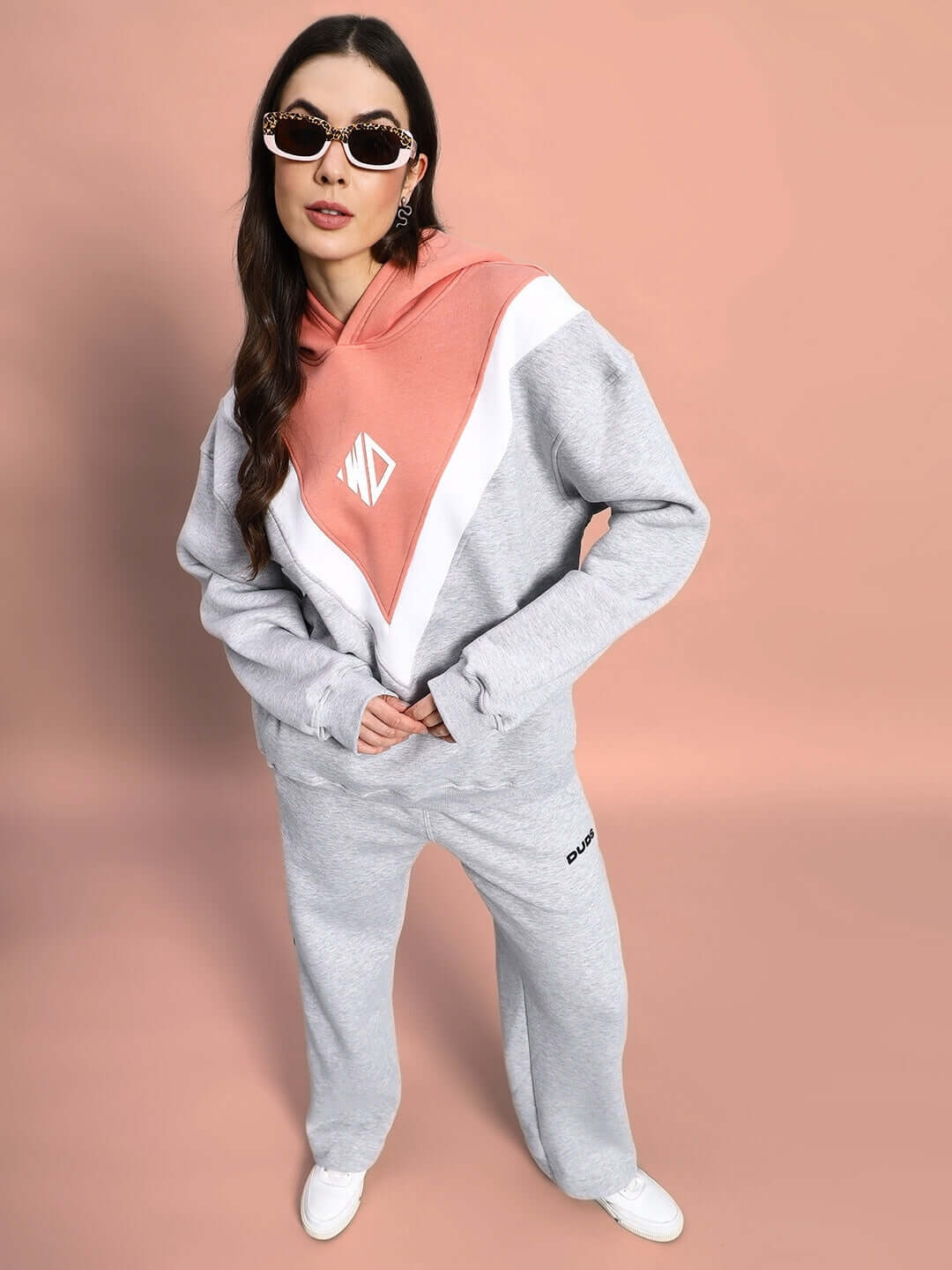 Woman wearing WOMEN POLAR COLORBLOCK CO-ORD GREY PEACH set, standing stylishly in athleisure outfit with sunglasses.