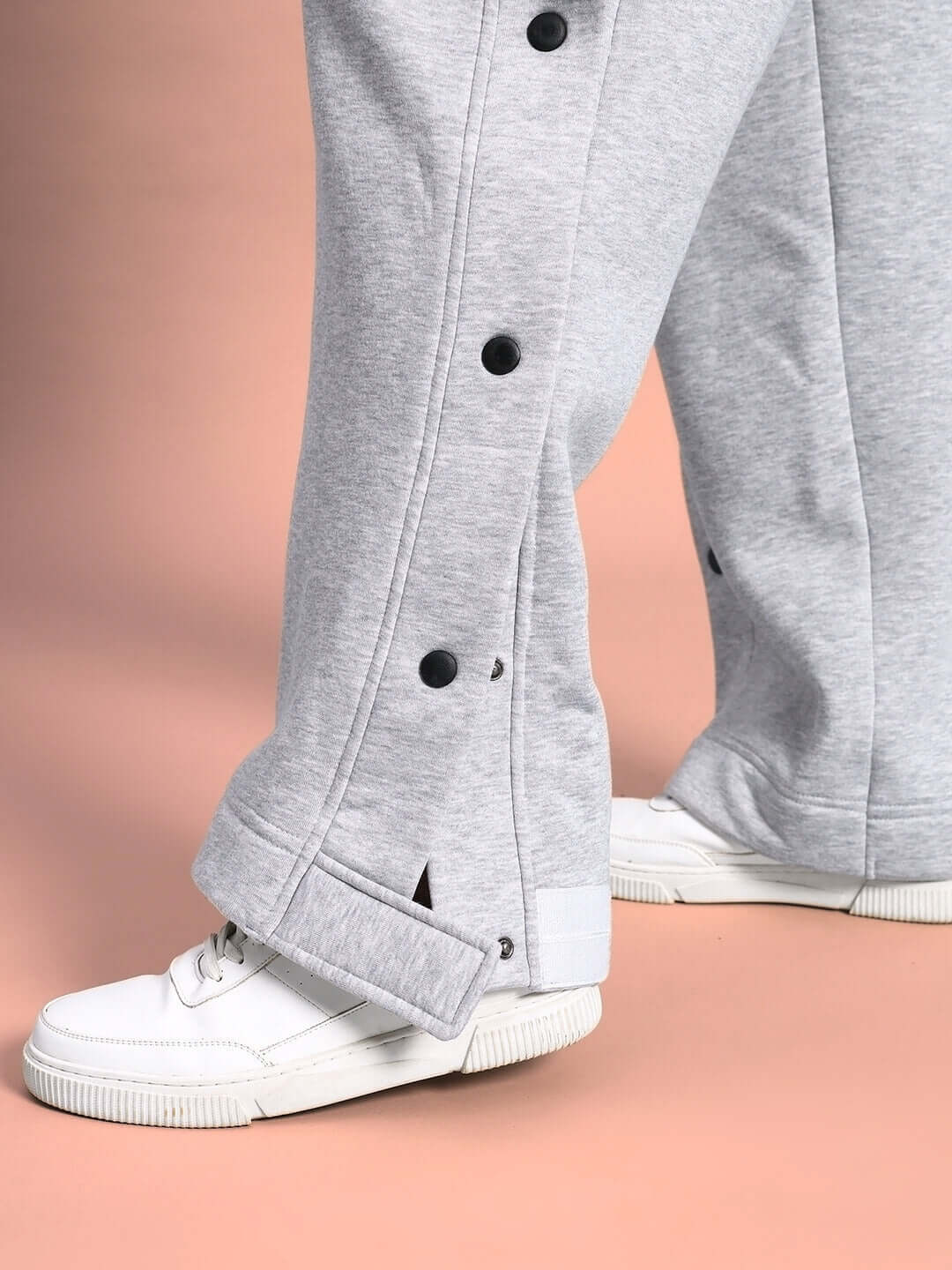 Close-up of grey women's polar fleece jogger with button details, paired with white sneakers. Ideal for comfort and style.