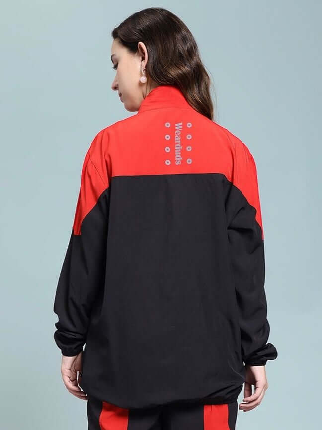 Back view of WOMEN POWER BLOCK RELAXED FIT JACKET BLACK RED with black base and red accents, worn by a woman.
