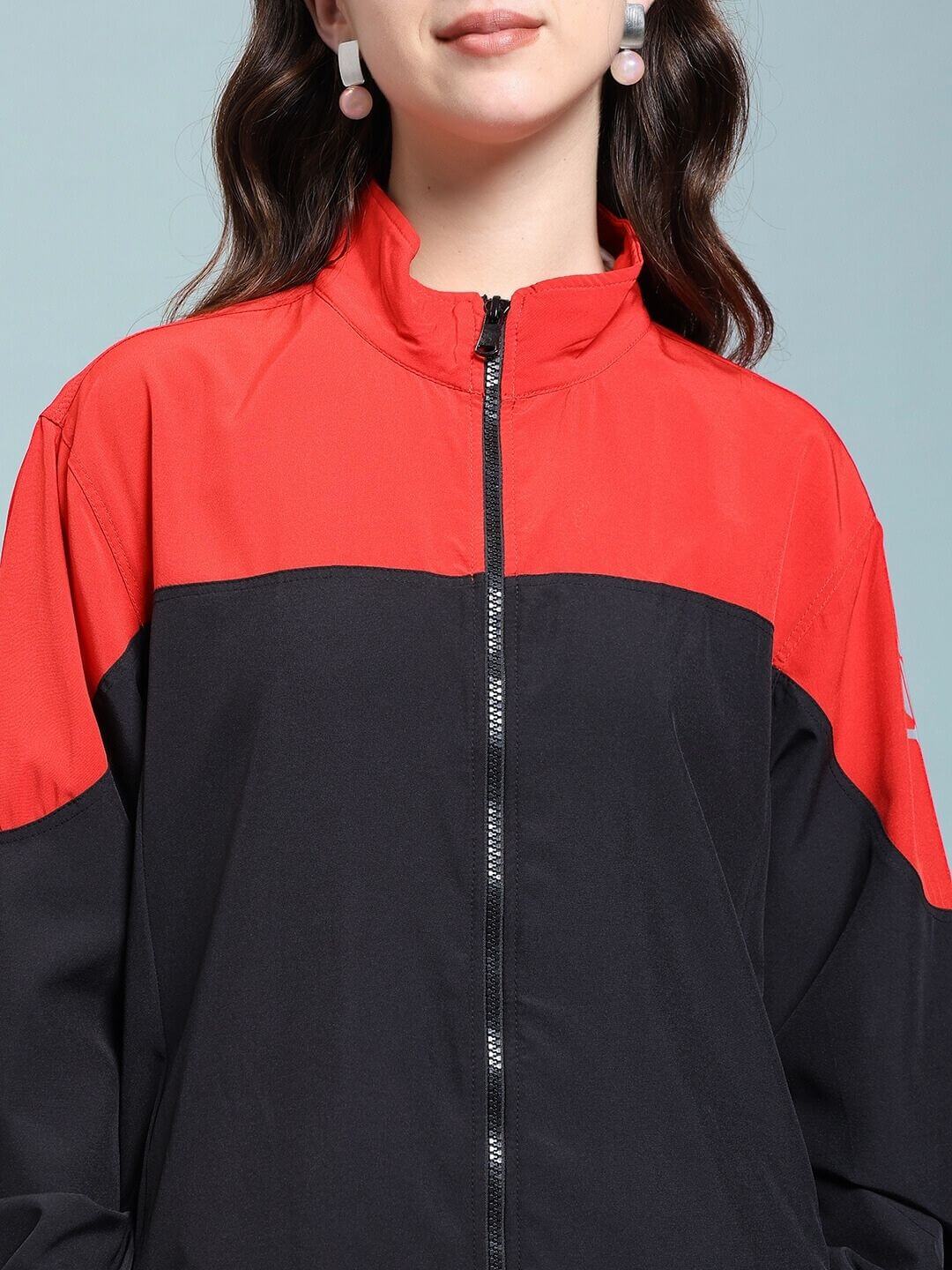 Woman wearing WOMEN POWER BLOCK RELAXED FIT JACKET BLACK RED with bold red and black design, showcasing streetwear style.