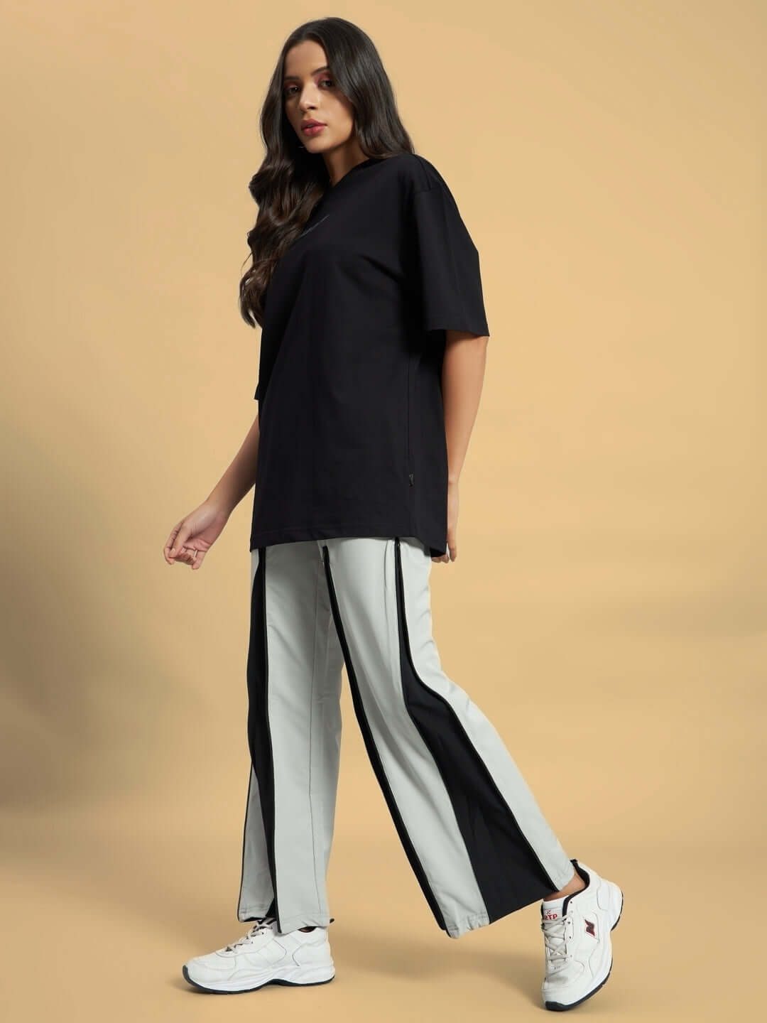 Model wearing Women's Primo Parachute Cargo Pants in grey with black side panels, paired with a black top and white sneakers.