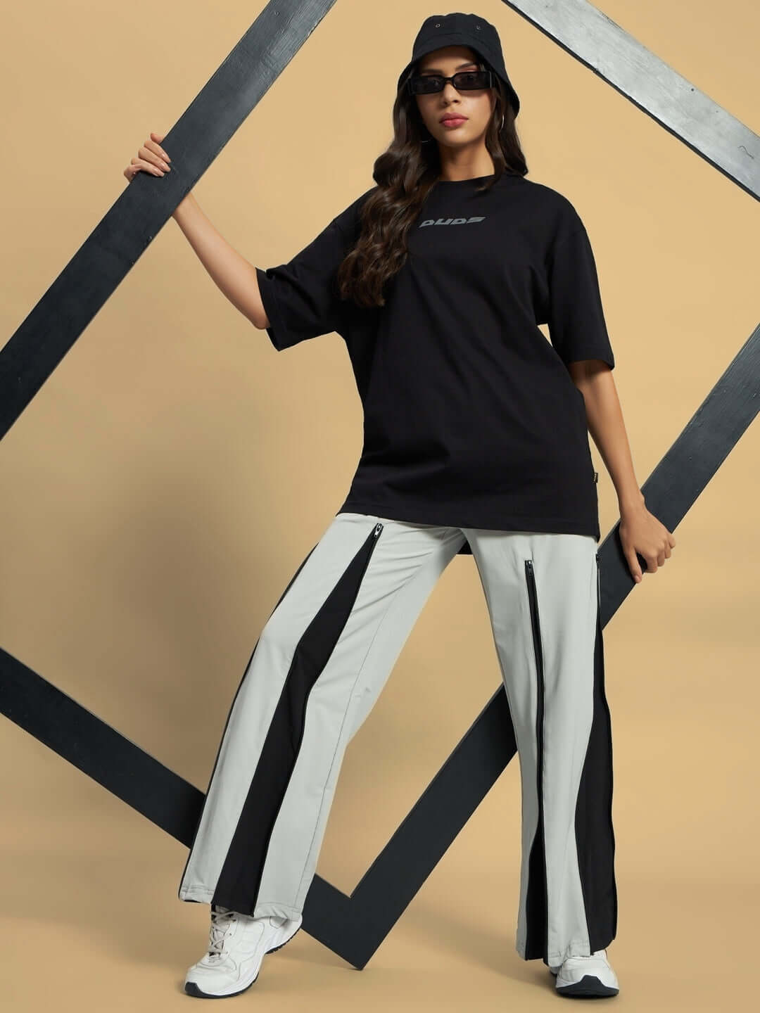 Model wears Women's Primo Parachute Cargo Pants in grey, styled with a black tee and hat, showcasing sporty and fashionable attire.