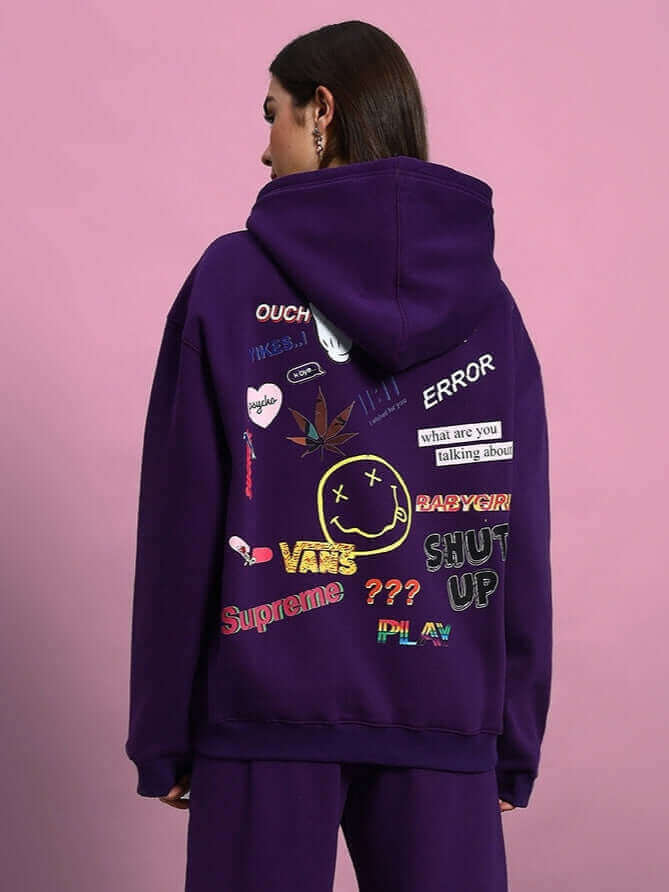 Woman wearing WOMEN SUPREME FLEECE HOODIE PURPLE with graphic designs on the back, showcasing bold streetwear style.