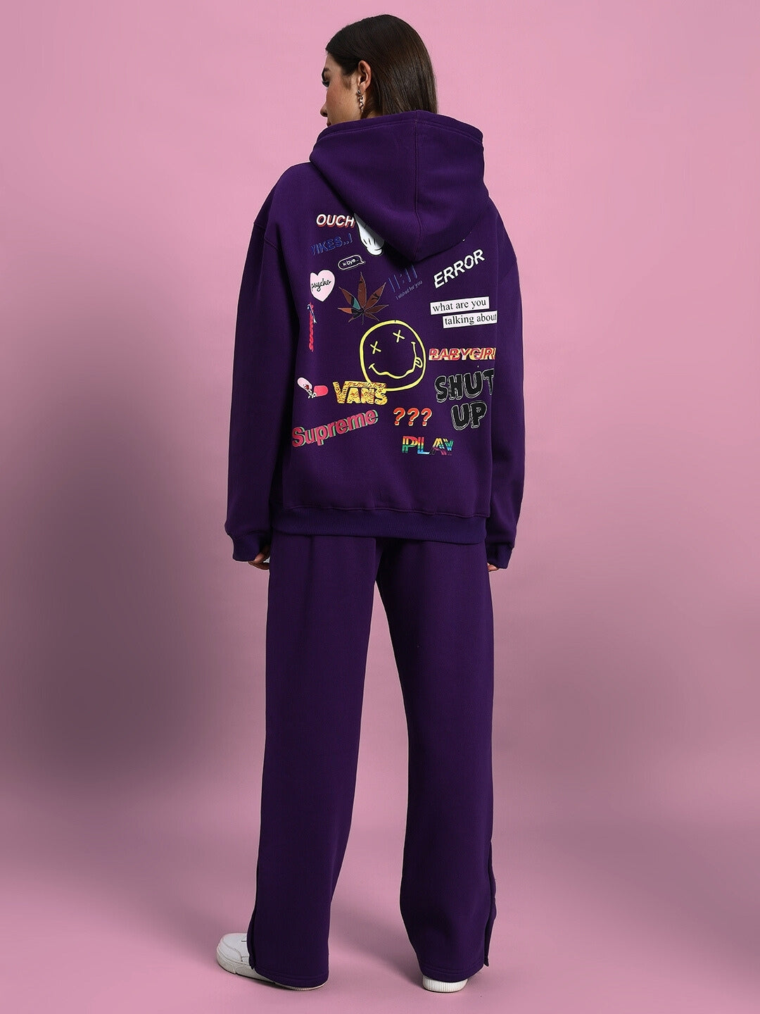 Woman wearing WOMEN SUPREME FLEECE CO-ORD PURPLE with graphic back details, standing against a pink backdrop.
