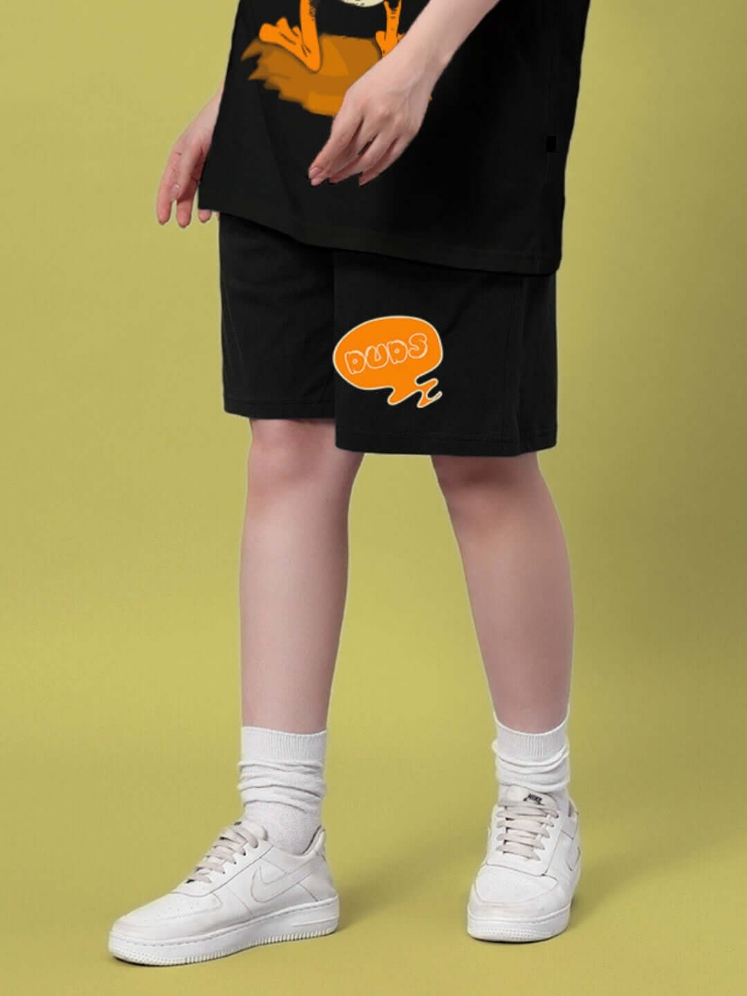 Woman wearing black Quack Off summer shorts with logo, paired with white socks and sneakers. Custom fit option available.