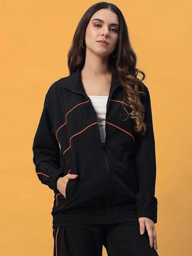 Woman wearing Women's Raider Co-ord Set in Black polyester from Color By Colours, standing against an orange background.