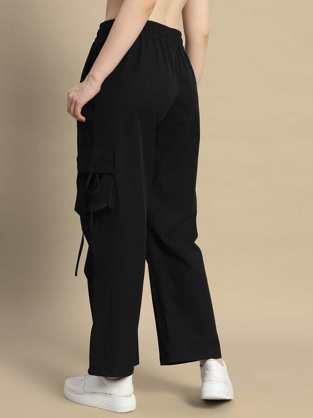 Back view of Women's Ramrod Parachute Cargo Pants in black, showcasing side pocket details, paired with white sneakers.