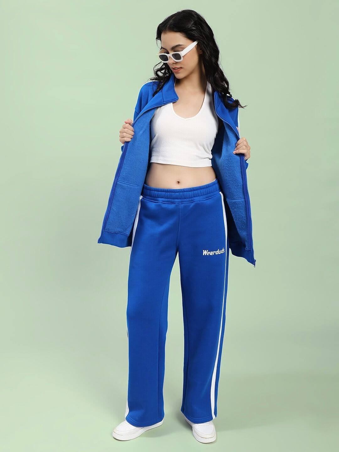 Woman wearing WOMEN RAPID STRIDE COTTON FLEECE JACKET ROYAL BLUE with casual white top and sunglasses, showcasing sporty chic style.