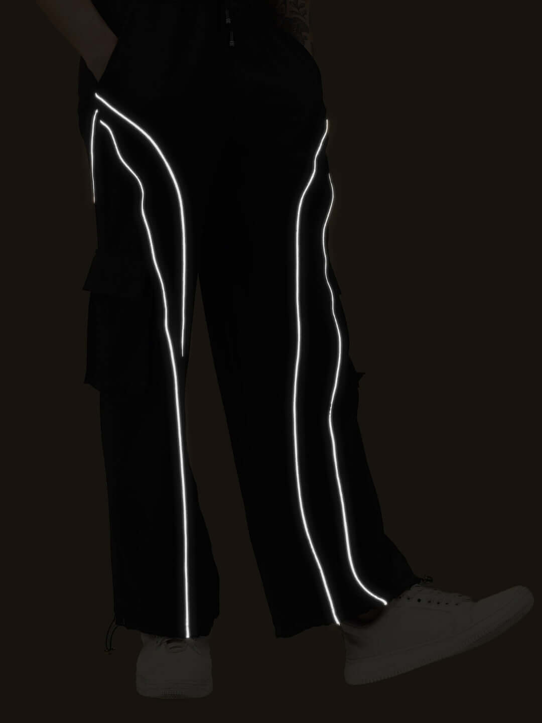 Women's black ray reflector parachute cargo pants with reflective stripes, customizable fit option available.