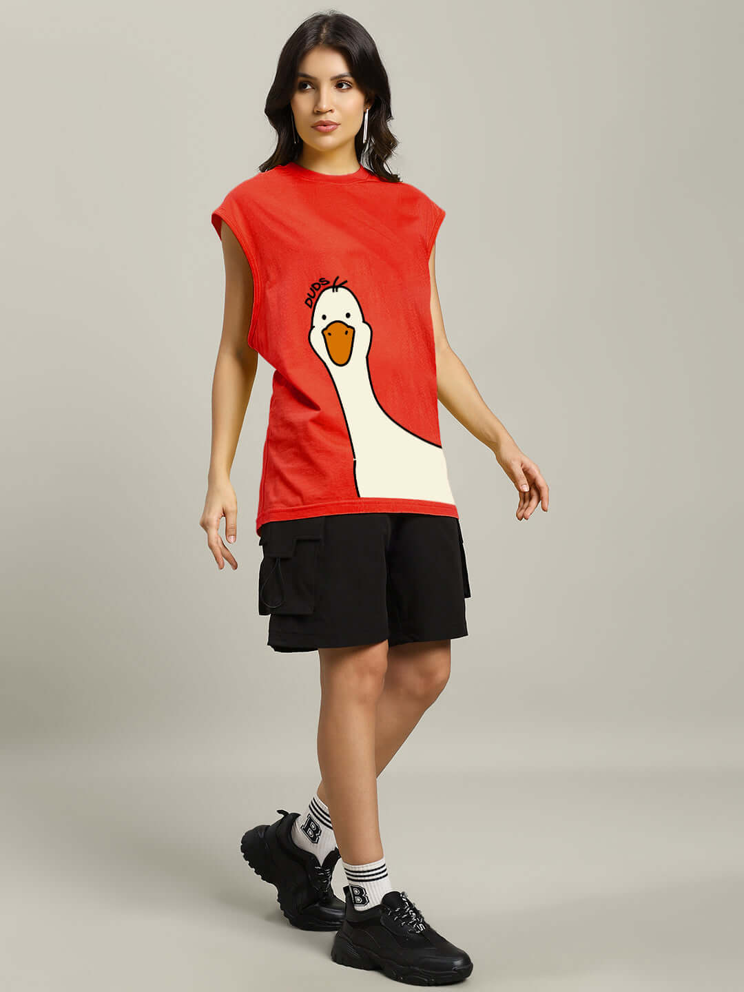 Woman wearing a red gym t-shirt with a duck graphic, styled with black shorts and sneakers for a relaxed athletic look.