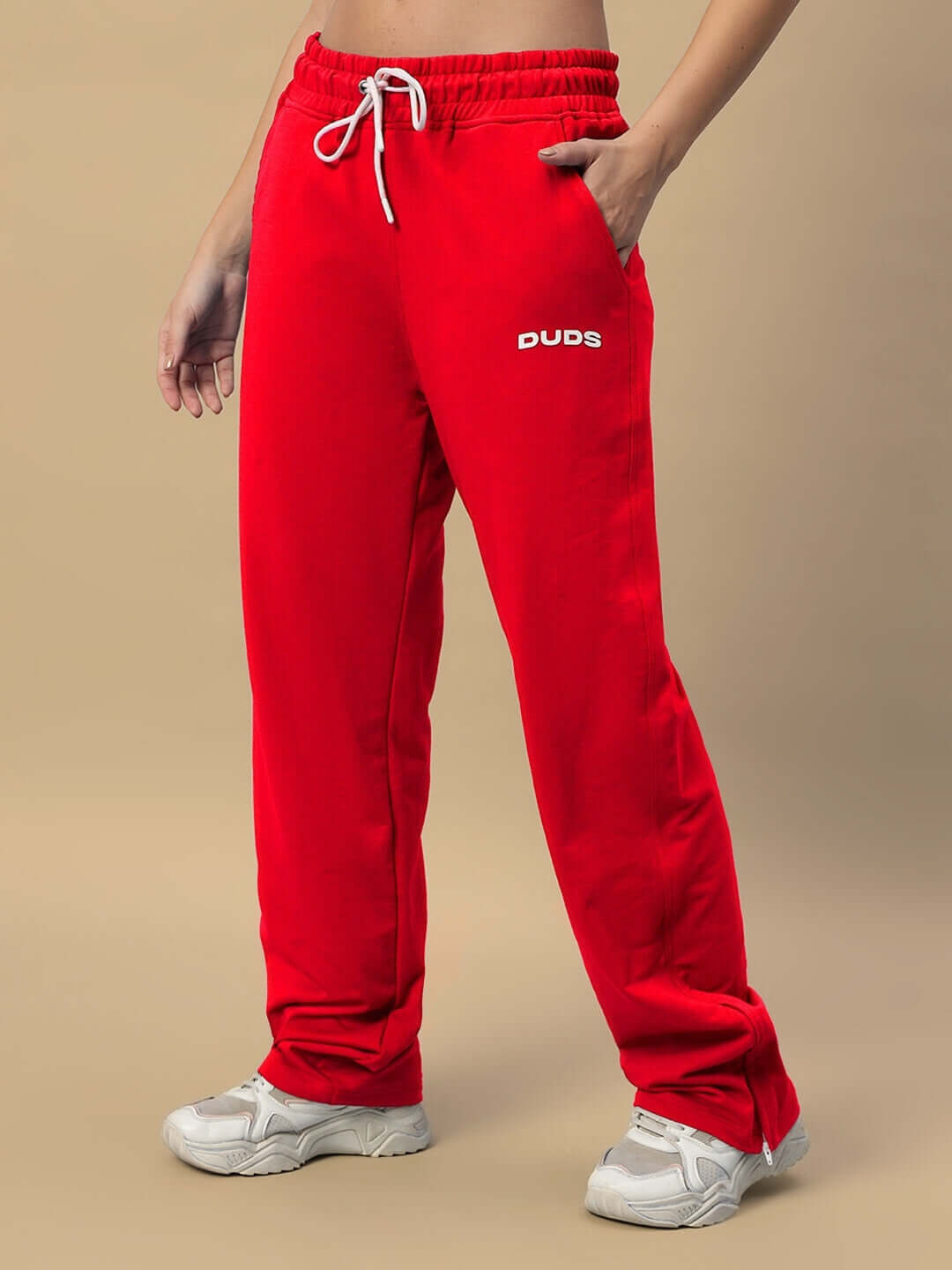 Model wearing red women's Hershey side slit joggers by DUDS, featuring elastic waistband and side pockets, paired with white sneakers.