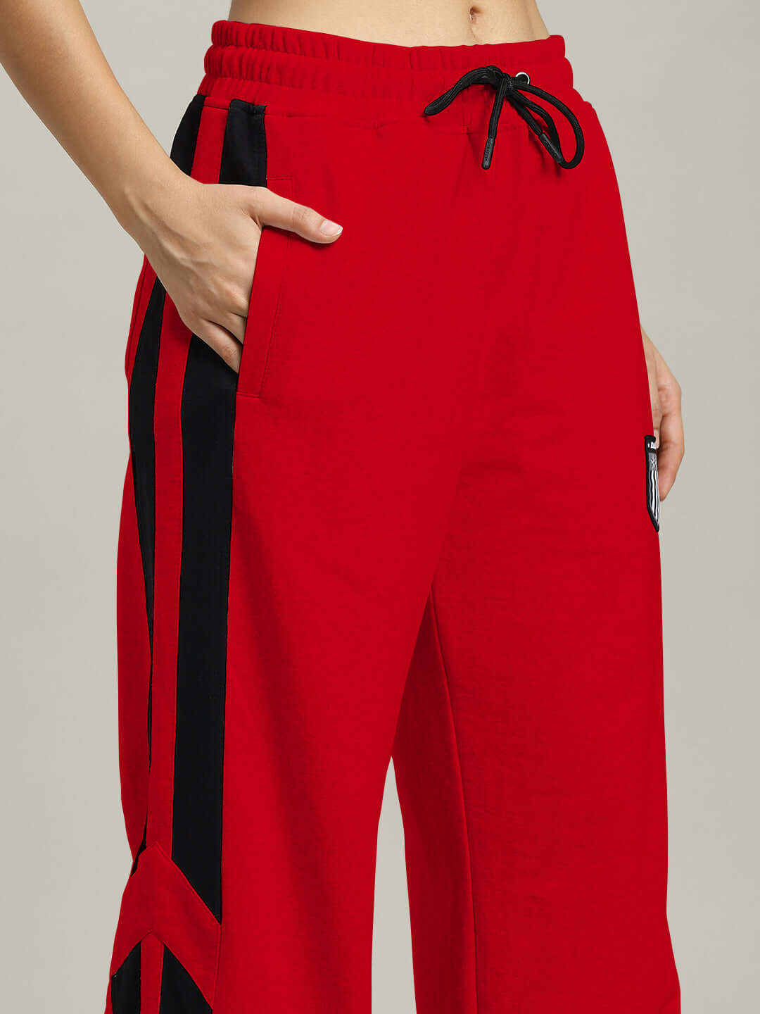 Women's red Royalson joggers by DUDS, featuring black side stripes and a drawstring waist.