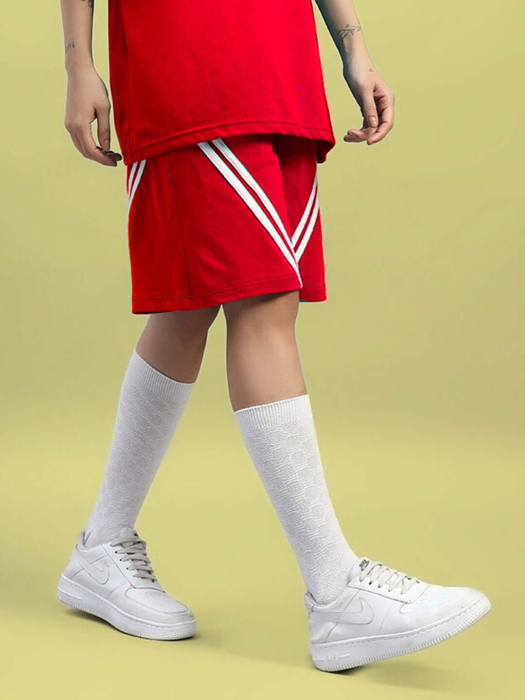 Model wearing Women's Star Jumper Regular Fit Red Shorts with white sneakers and knee-high socks.