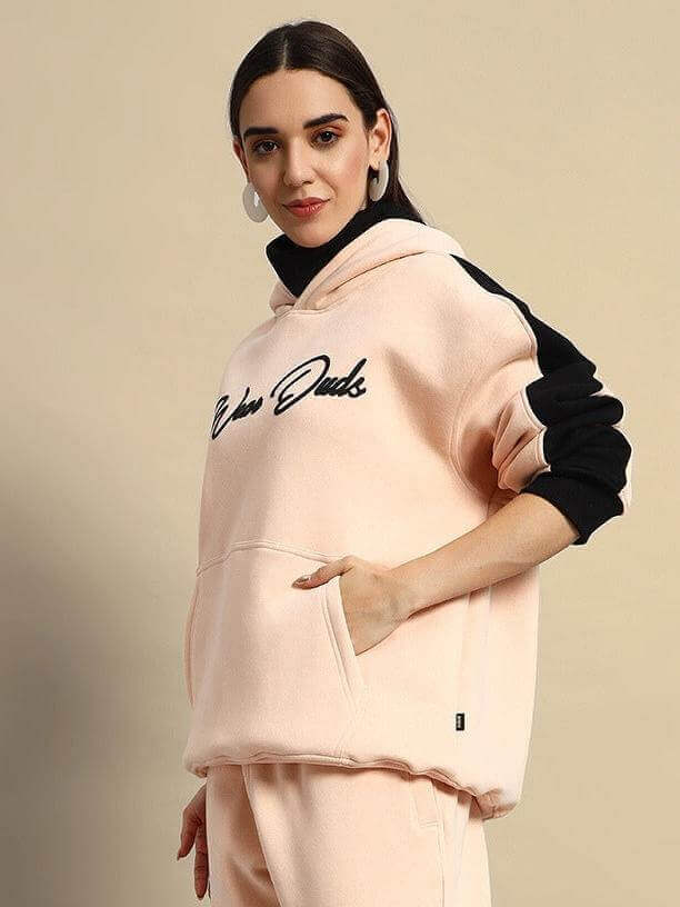 Women's beige-black fleece hoodie, with side pockets and black sleeve accents, styled for casual comfort.