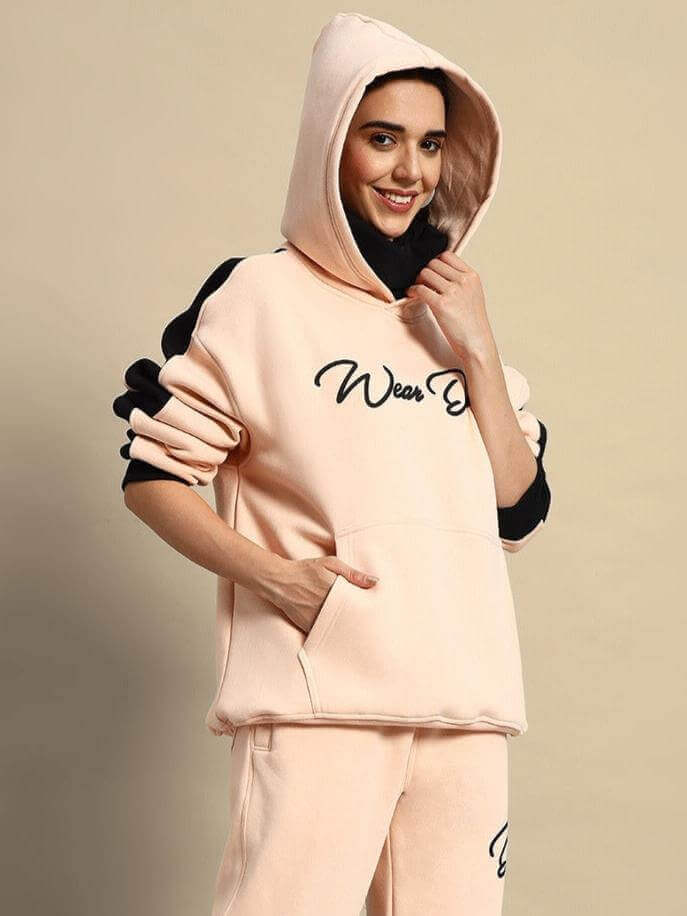 Woman wearing beige-black regiment fleece hoodie with hood up, stylish and comfortable outfit for casual wear.