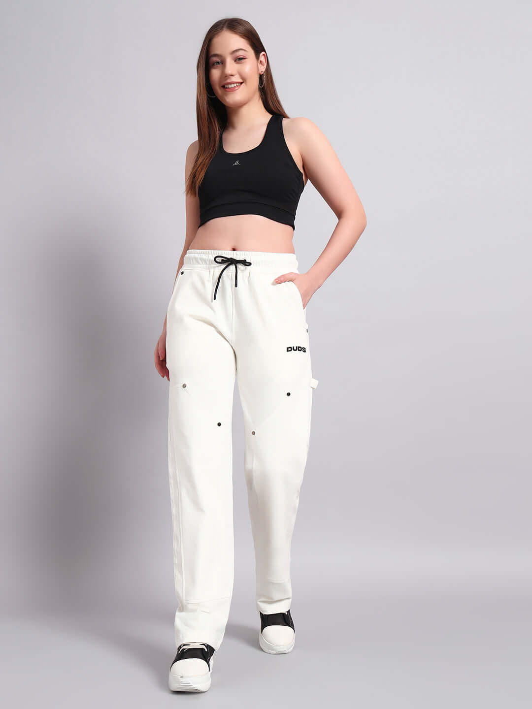 Woman wearing white relaxed-fit joggers from DUDS, paired with a black crop top.