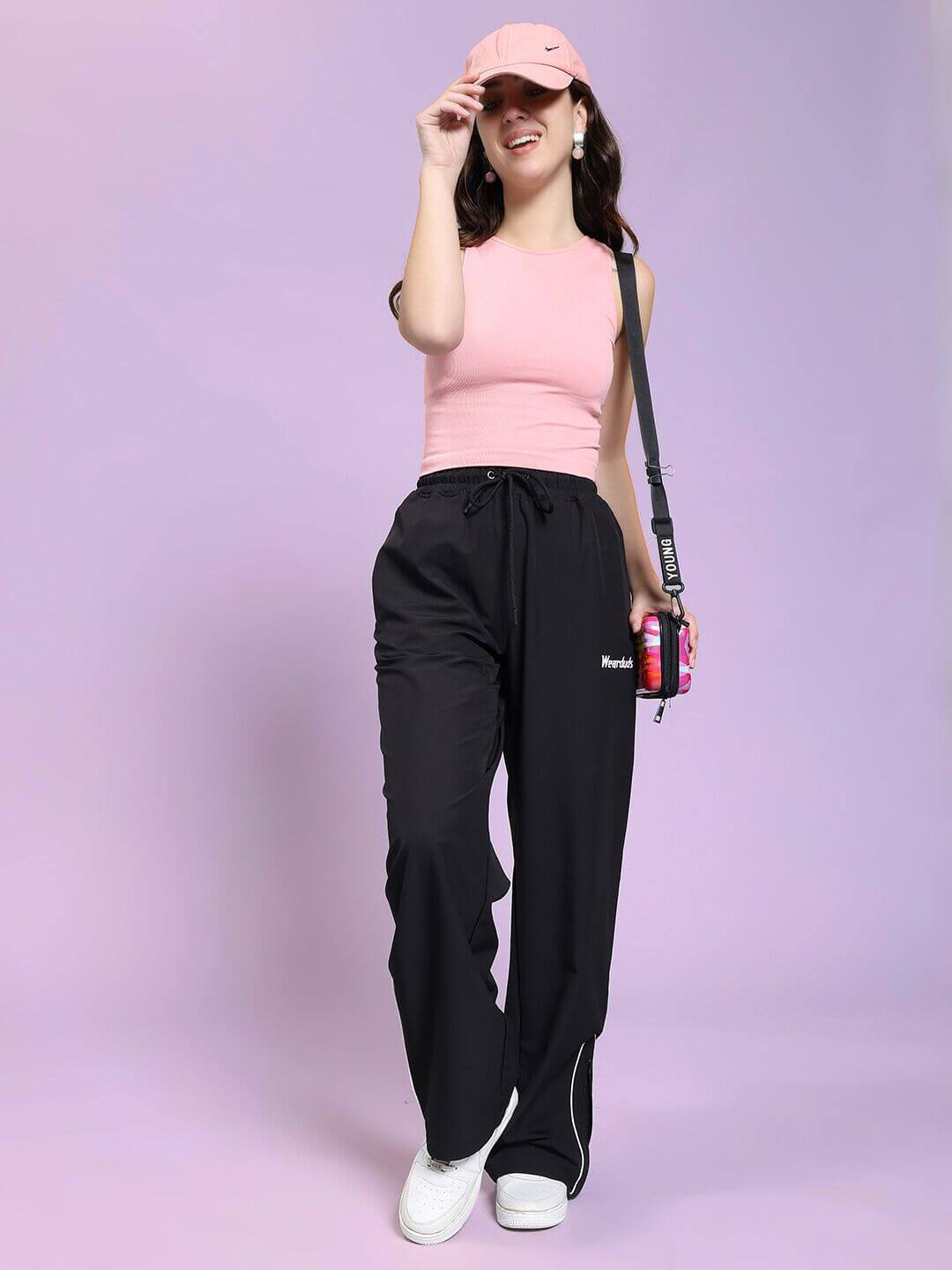 Woman wearing WOMEN PERFACT RELAXED-FIT JOGGER BLACK, pink top, and cap, showcasing casual chic style.