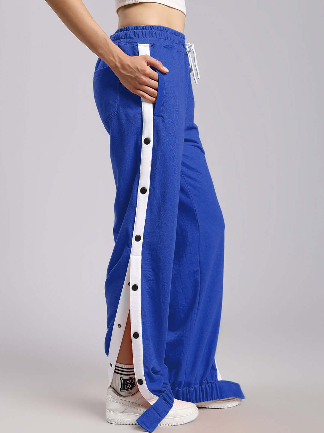 Woman wearing WOMENS MILLER RELAXED FIT JOGGERS BLUE with side buttons and white accents.