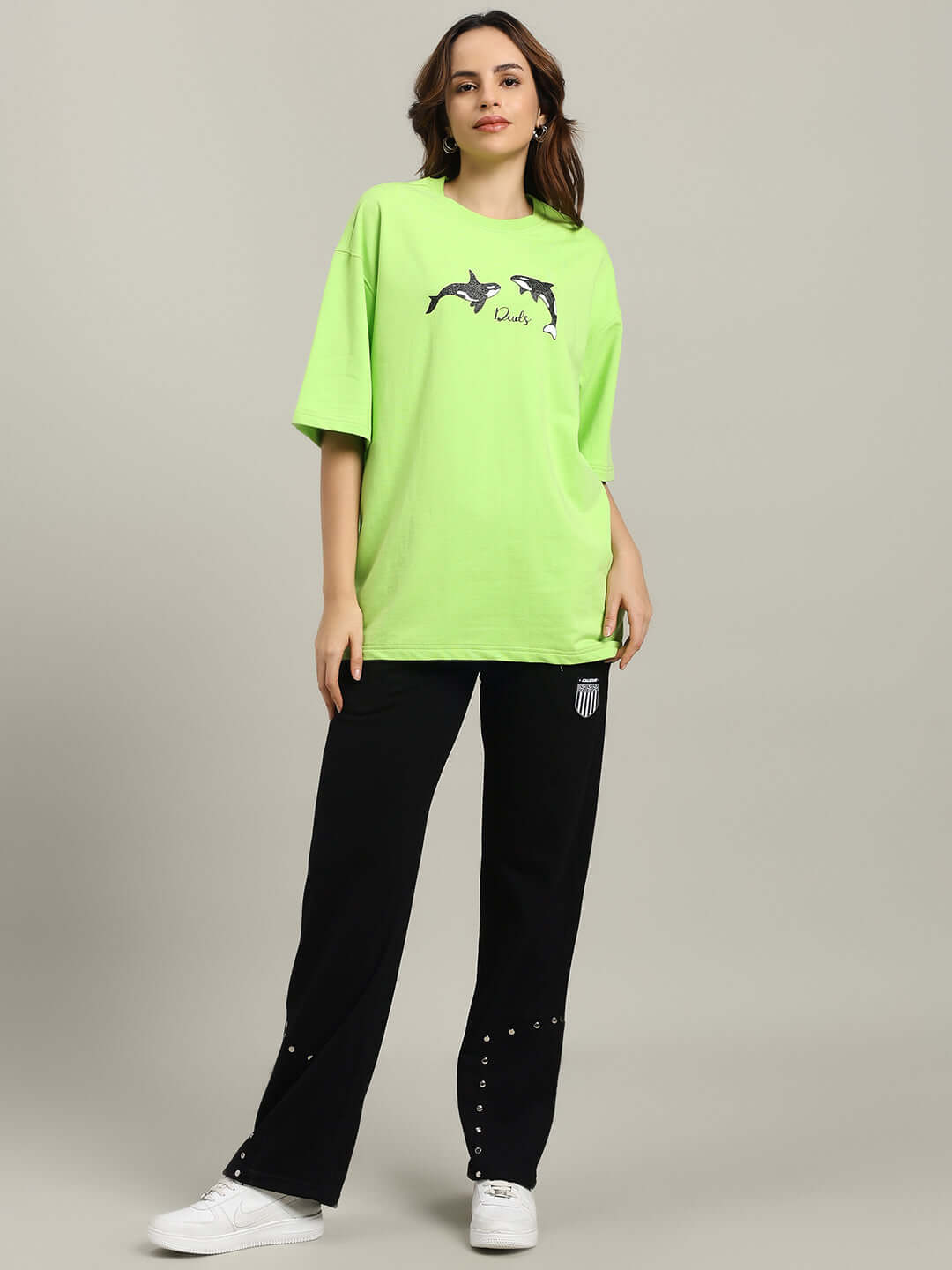 Model wearing WOMEN'S STUNNER RELAXED FIT JOGGER BLACK with green shirt, showcasing casual style.