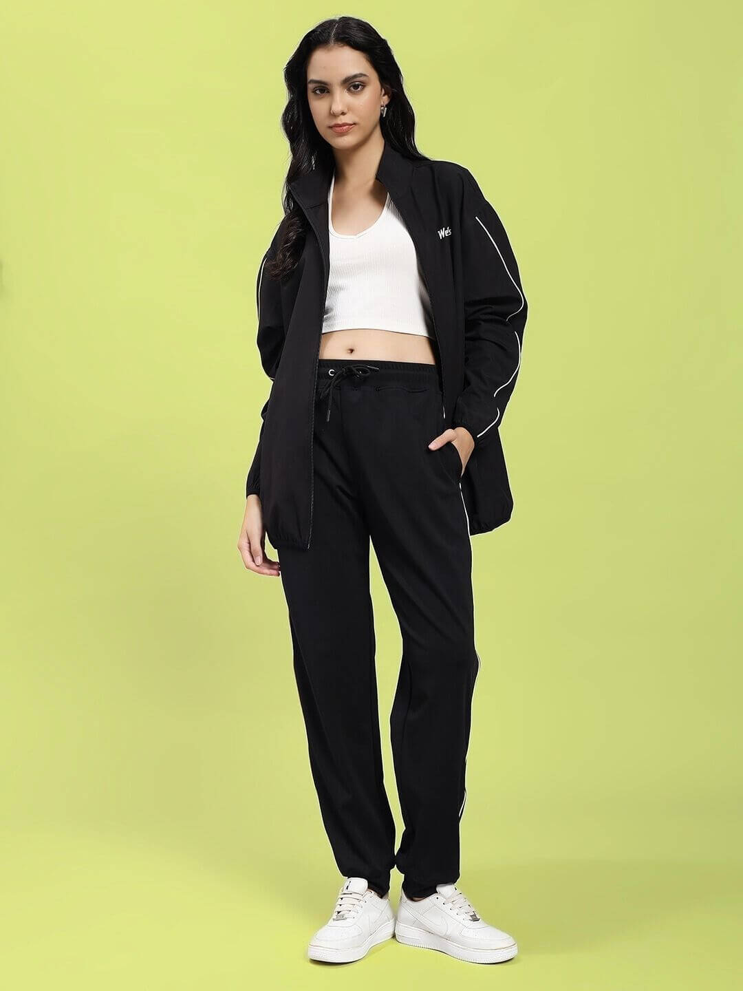 Woman wearing WOMEN RELIGHT RELAXED FIT JACKET BLACK with reflective trims, showcasing modern urban style and comfort.