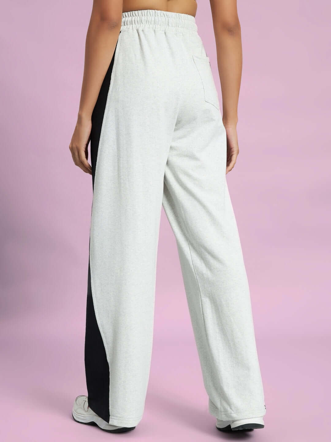 Back view of women's grey joggers with black side contrast, made from melange fabric, showcasing relaxed fit and custom size options by DUDS.