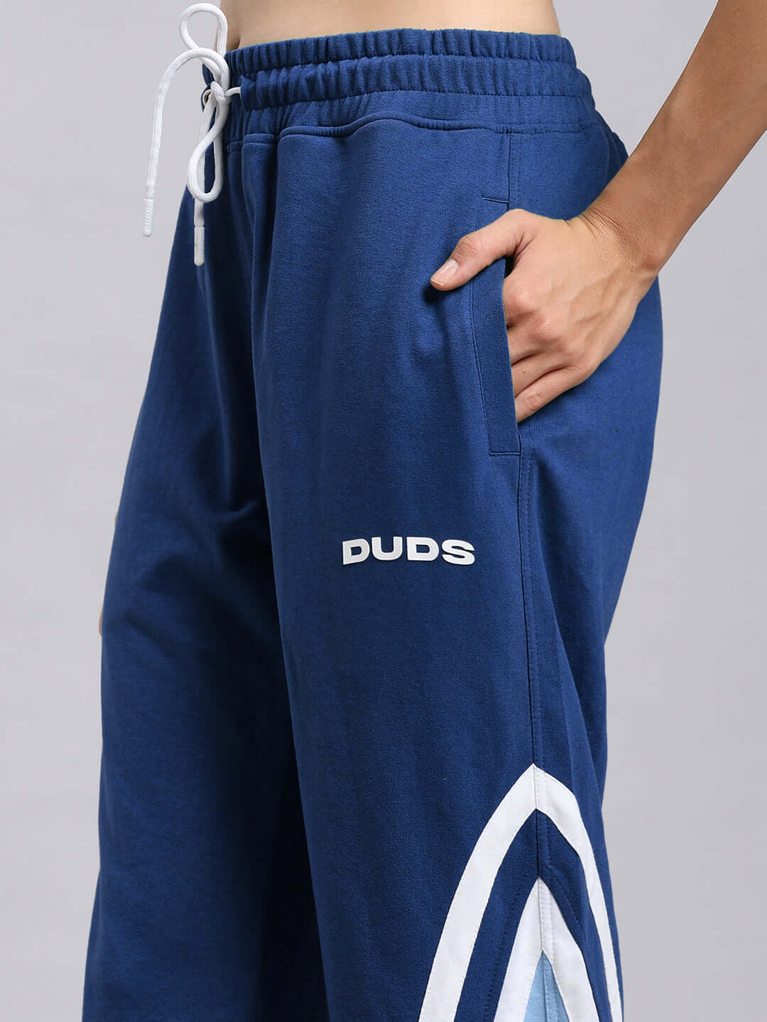Model wearing WOMEN'S RIO ONE Relaxed Fit Joggers in blue by DUDS, featuring side pockets and custom fit option.