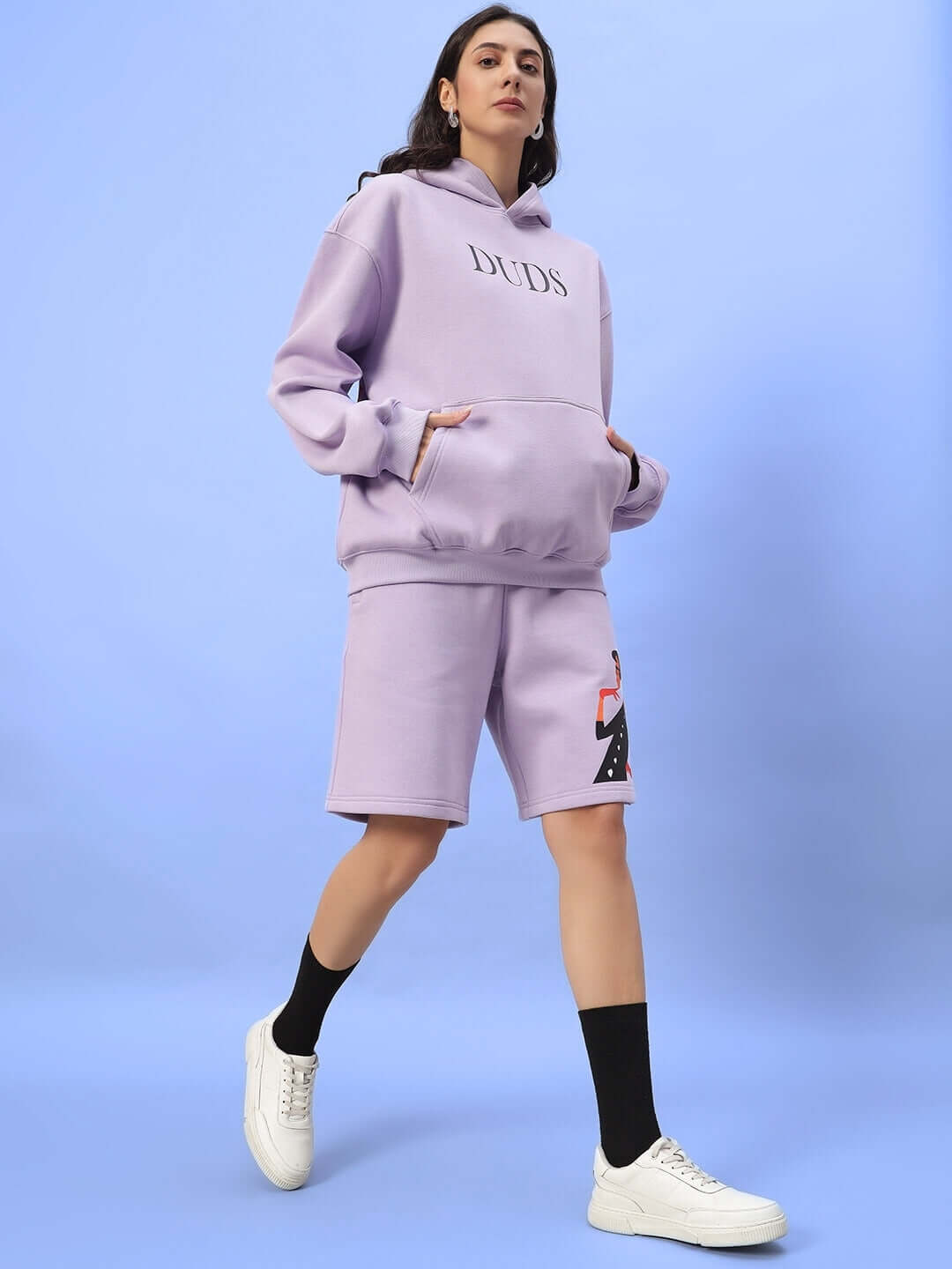 Model wearing WOMEN RITZY FLEECE SHORTS LILAC and matching hoodie, showcasing comfortable and stylish outfit for casual wear.
