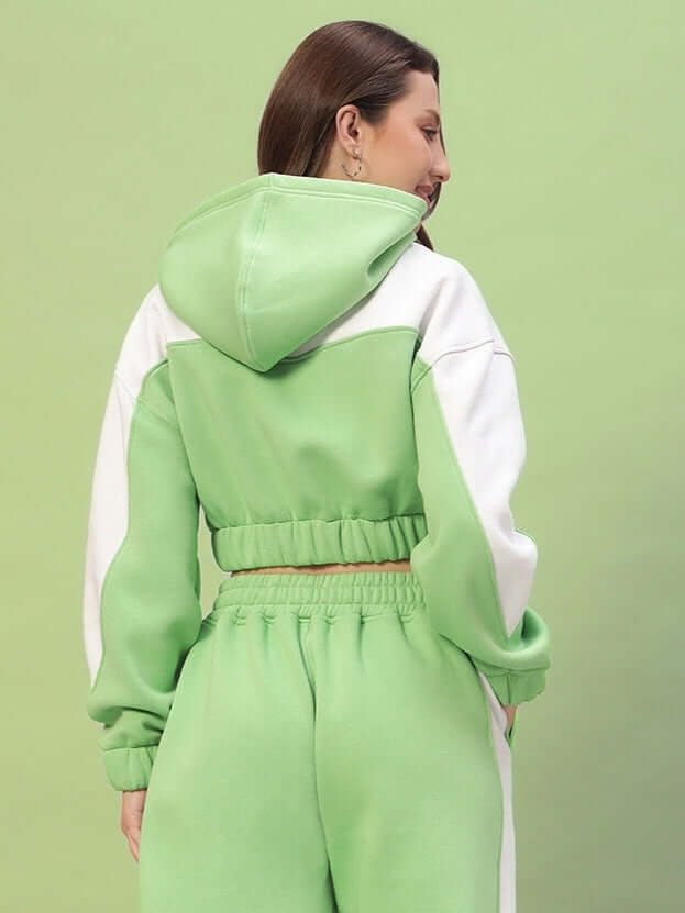 Woman wearing green and white colorblock co-ord set, featuring a hooded top and pants, showcasing a trendy and modern fashion style.