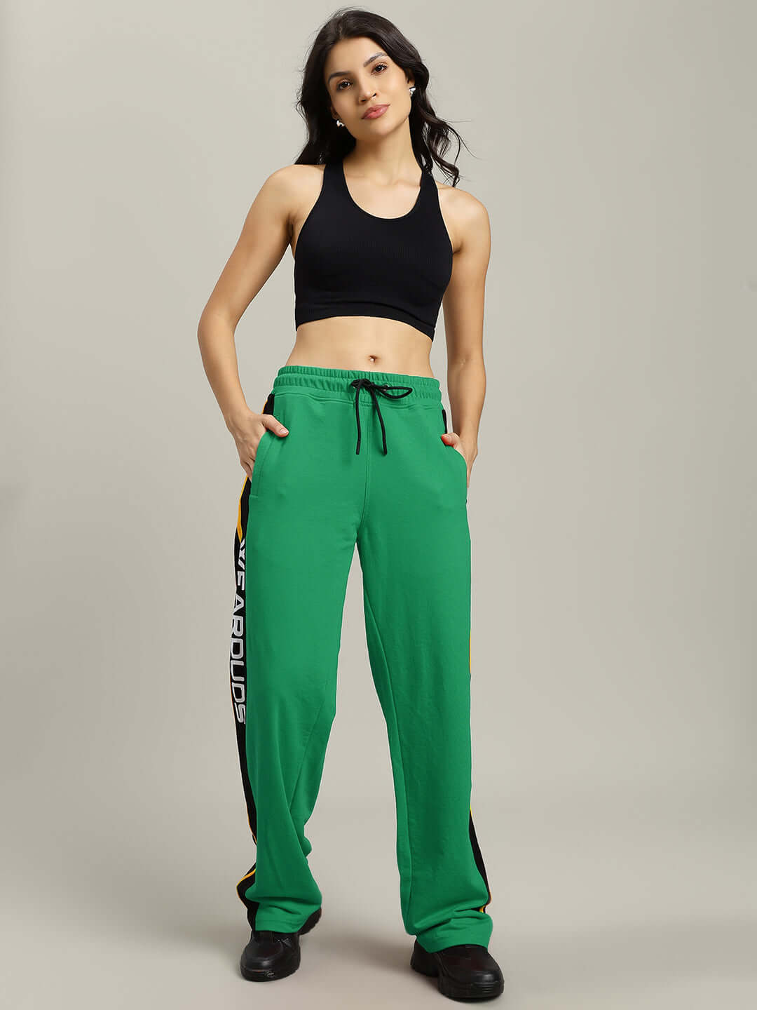 Woman wearing WOMENS ROGER RELAXED-FIT JOGGERS GREEN with black tank top, featuring elastic waistband and adjustable drawstrings.