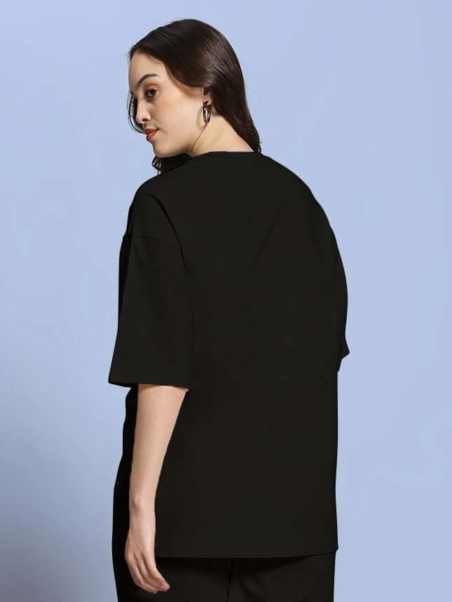 Woman wearing WOMEN ROSE CHARM OVER-SIZED T-SHIRT BLACK, showcasing modern oversized silhouette from back view.