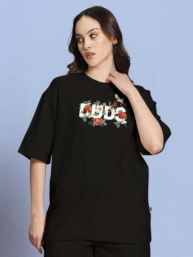 Woman wearing WOMEN ROSE CHARM OVER-SIZED T-SHIRT BLACK, showcasing its modern oversized silhouette and chic streetwear style.