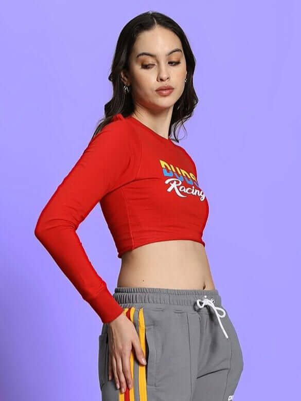 Women's red racing print crop top with long sleeves, styled with grey track pants, showcasing a sporty and modern look.