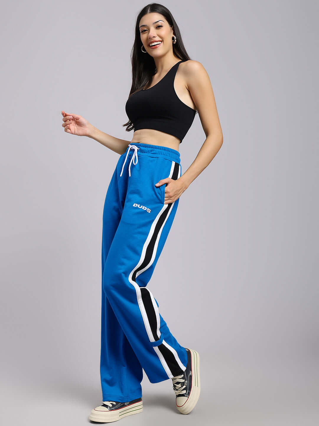 Woman wearing WOMENS ROSSTON FLAT-OUT RELAXED FIT JOGGERS BLUE with black top, showcasing relaxed streetwear style.