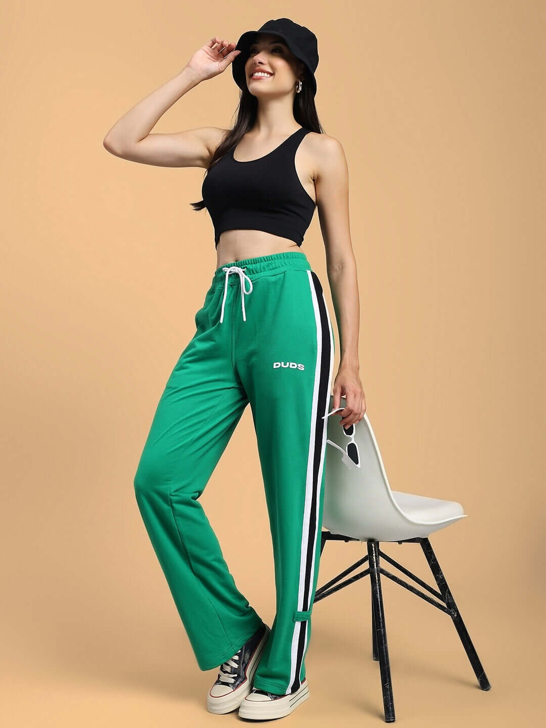 Model wearing DUDS Women's Rosston Flat-Out Relaxed Fit Joggers in green, showcasing casual style with black tank top and sneakers.