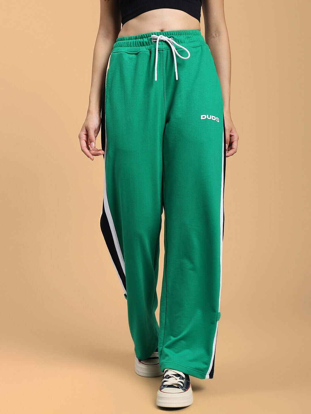 Woman wearing green Women's Rosston Flat-Out Relaxed Fit Joggers by Duds, featuring adjustable waist tie and side stripes, with sneakers.