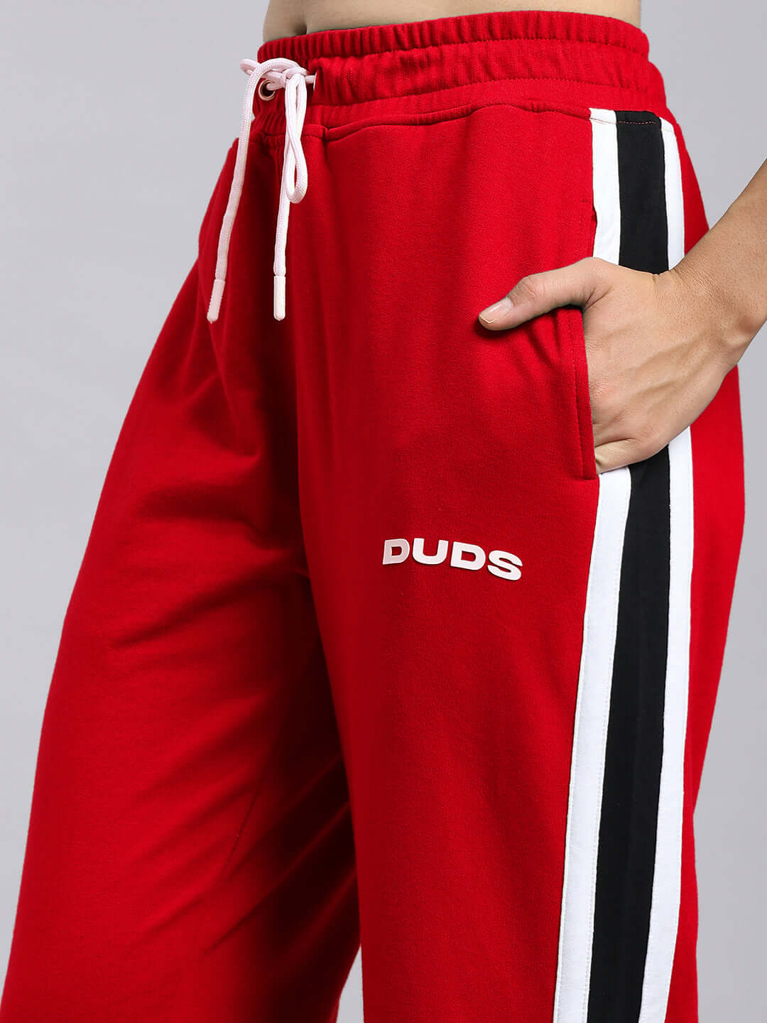 Red women's joggers with black and white side stripes, featuring DUDS logo, relaxed fit design with drawstring waistband.
