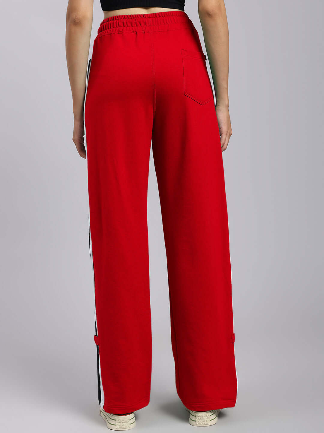Model wearing red Women's Rosston Flat-Out Relaxed Fit Joggers from DUDS with rear view, elastic waistband, and side stripes.