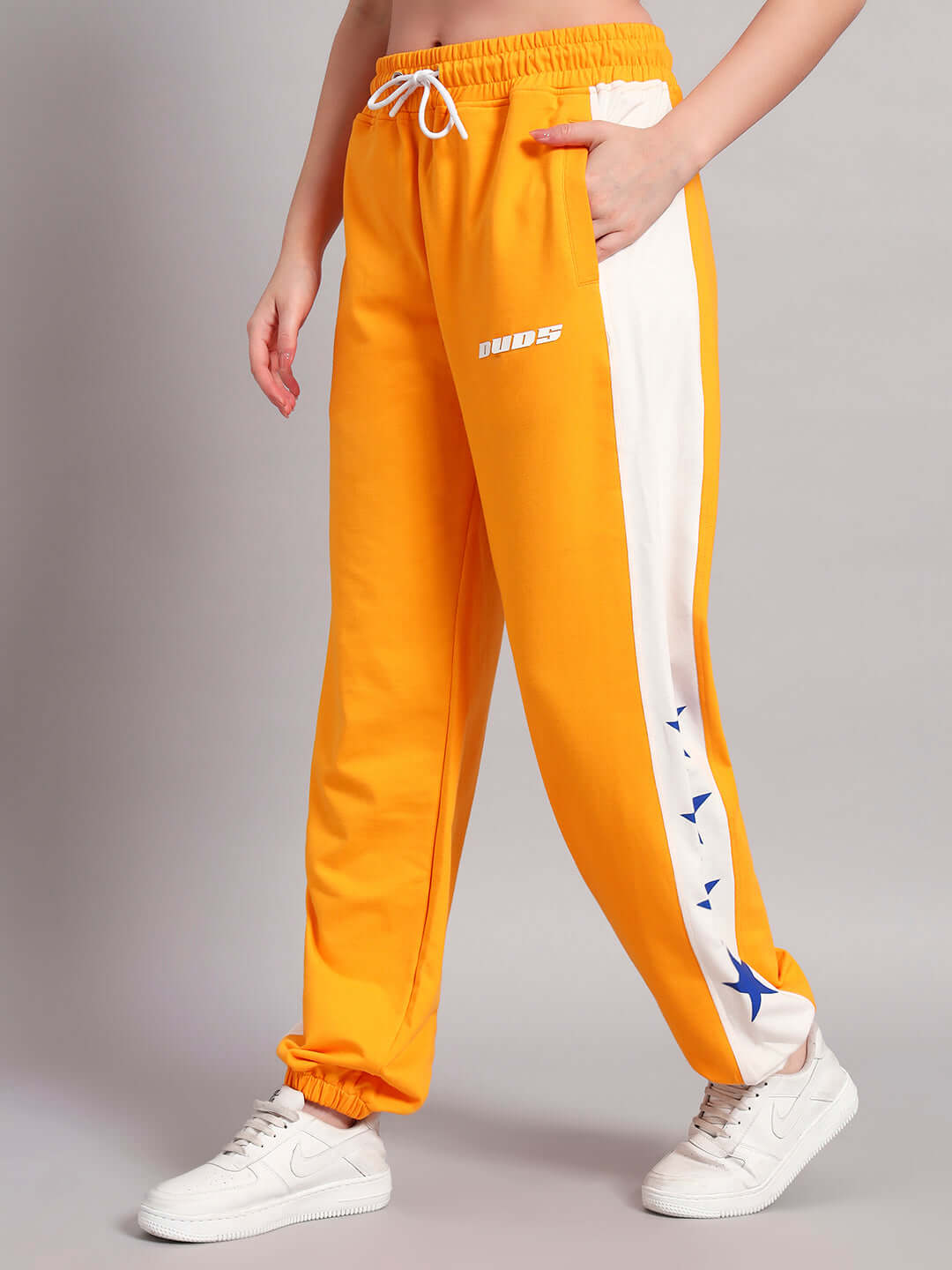 Woman wearing orange-white relaxed fit joggers with side stars, showcasing the comfortable design of DUDS Rox Primer.