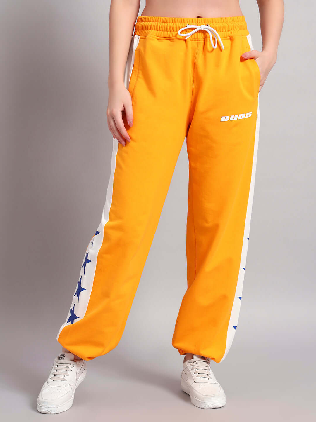 Women's Rox Primer Relaxed Fit Joggers in orange and white with star pattern, shown from the front with hands in pockets.