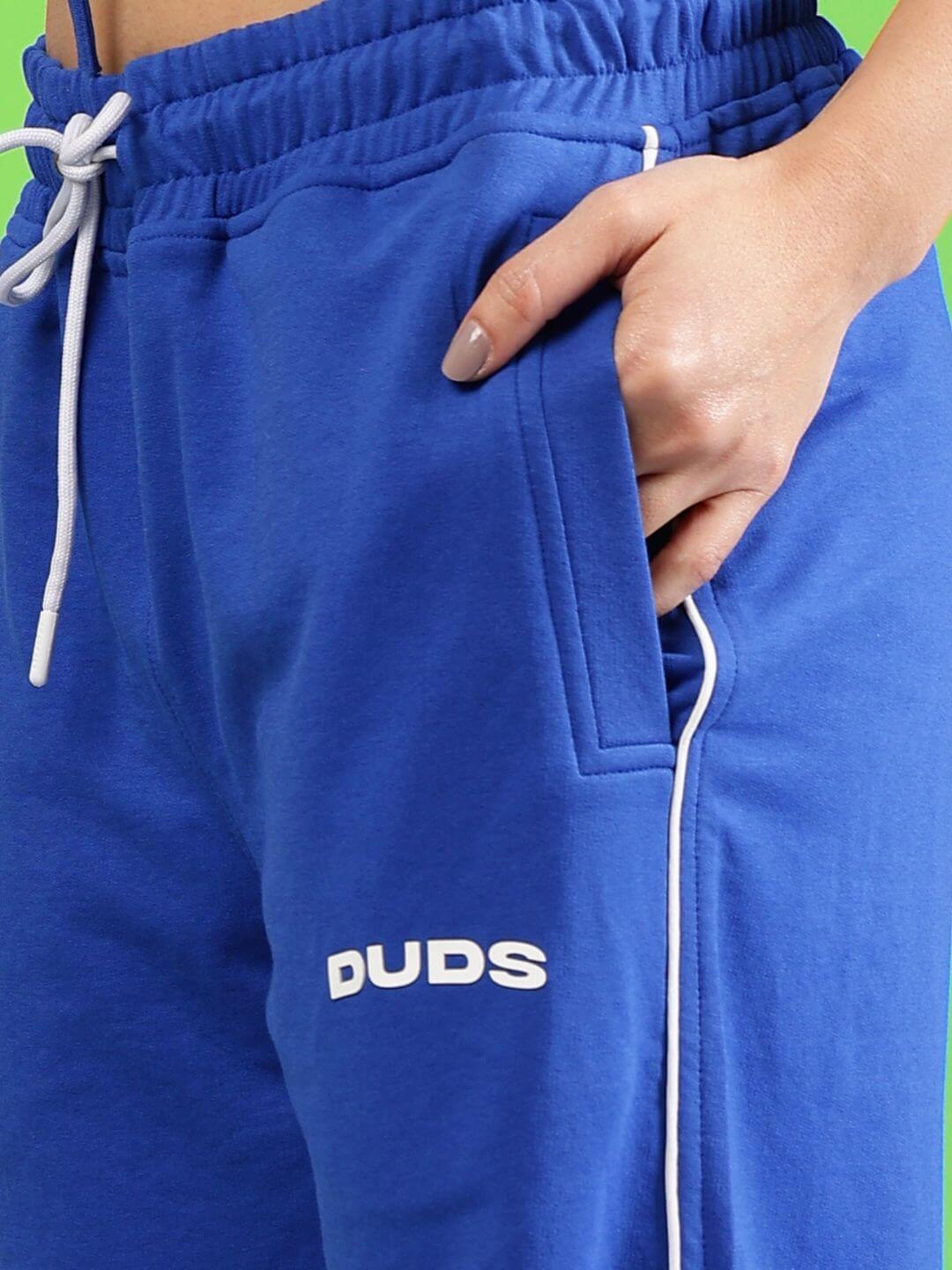 Women's blue joggers with white 'DUDS' logo, featuring an elastic waistband and pocket detail, made from premium heavy gauge fabric.