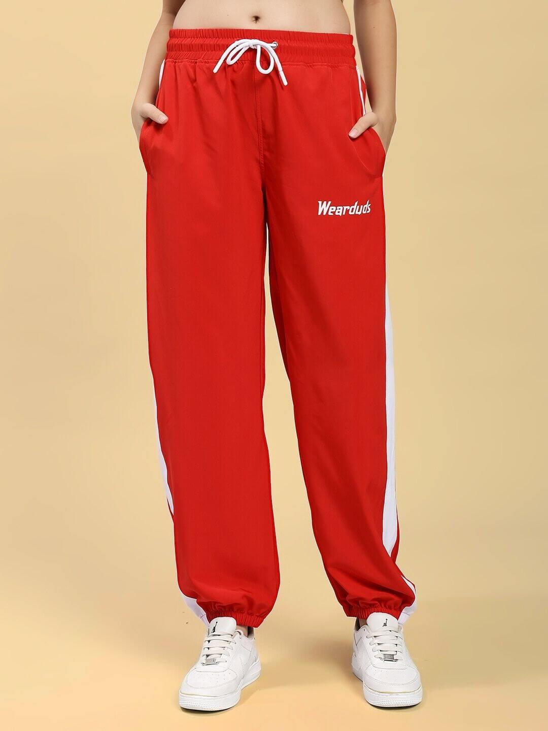 Model wearing WOMEN ROYAL COMFORT RELAXED FIT CO-ORD SET RED pants with white stripe detail and sneakers.