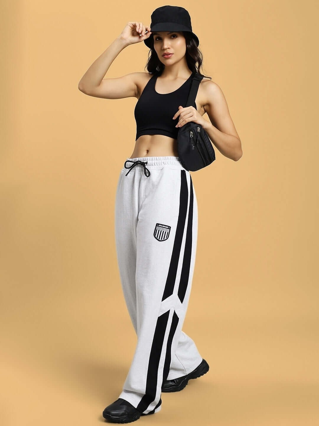 Woman wearing WOMEN'S ROYALSON JOGGERS MELANGE-GREY with black top and hat, holding a bag.