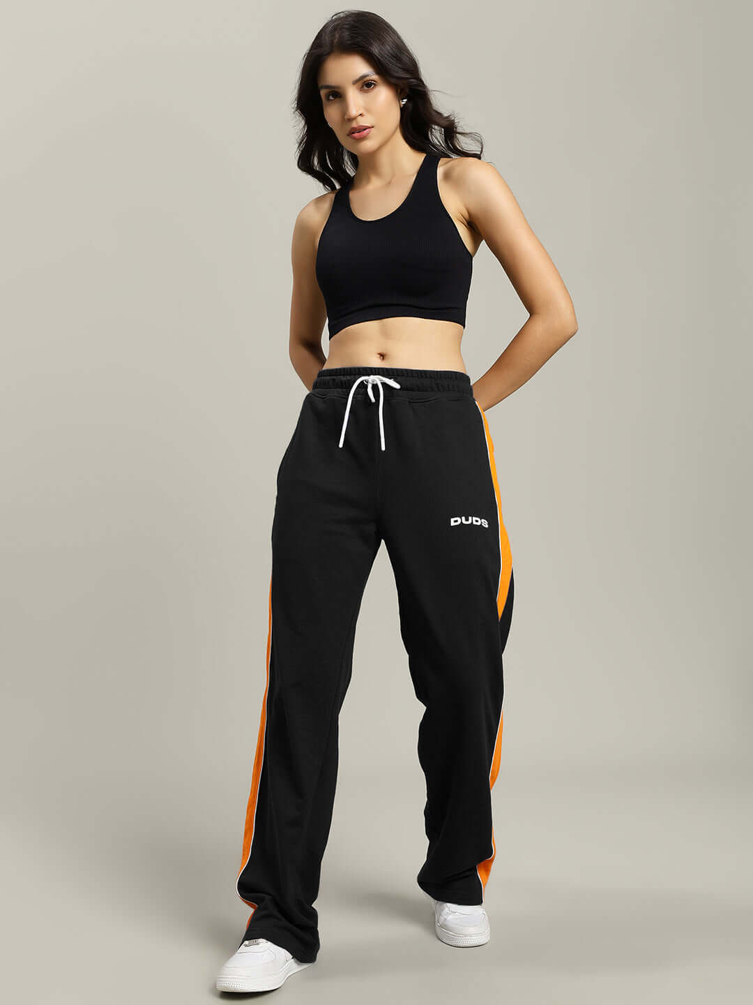 Model wearing WOMENS SANFORD STRIPE JOGGERS BLACK with an orange side stripe, showcasing sporty style and comfort.