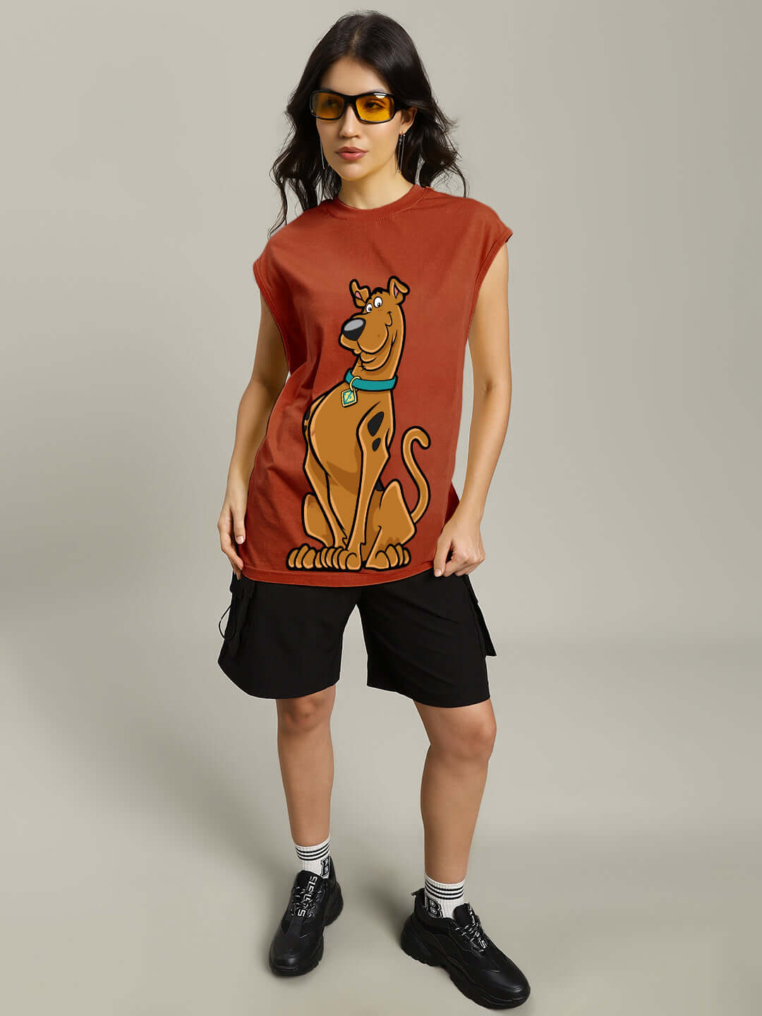 Woman wearing a brown Scooby Doo gym t-shirt with graphic print, paired with black shorts and sunglasses.