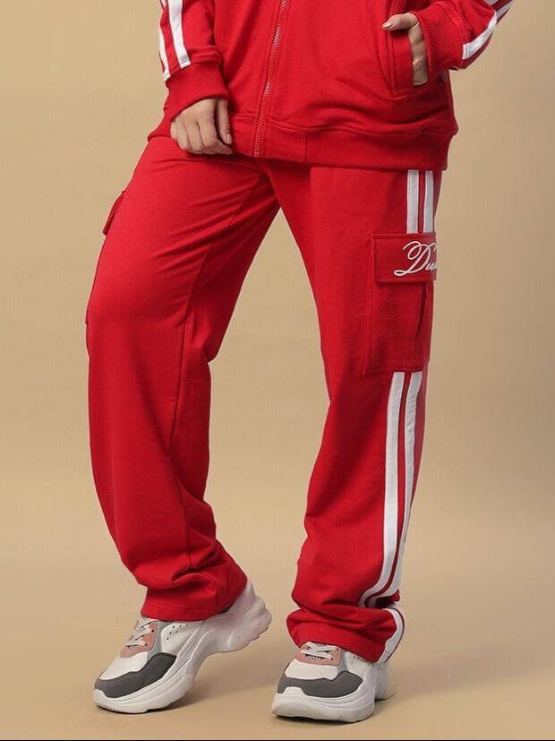 Woman wearing red joggers with white stripes, showcasing Women's Scotia Stripe Joggers by DUDS, available for customized sizing.