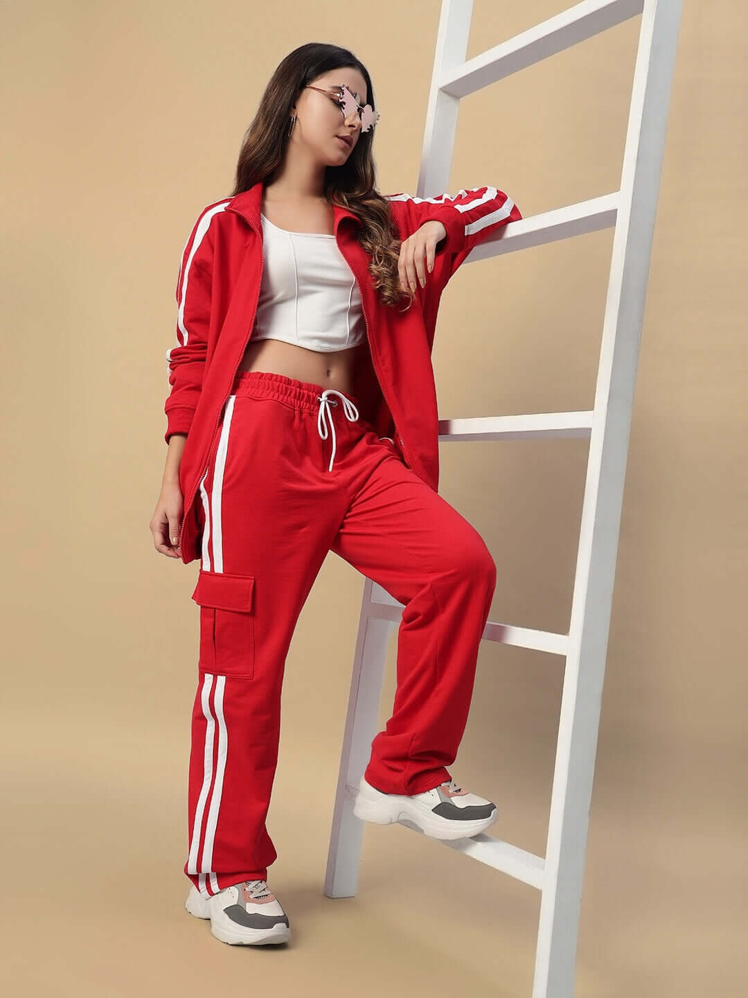 Model wearing Women's Scotia Stripe Joggers in red, featuring white stripes and casual styling, posing with a casual look on a ladder.